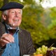 old man wearing a beret holding a glass of wine